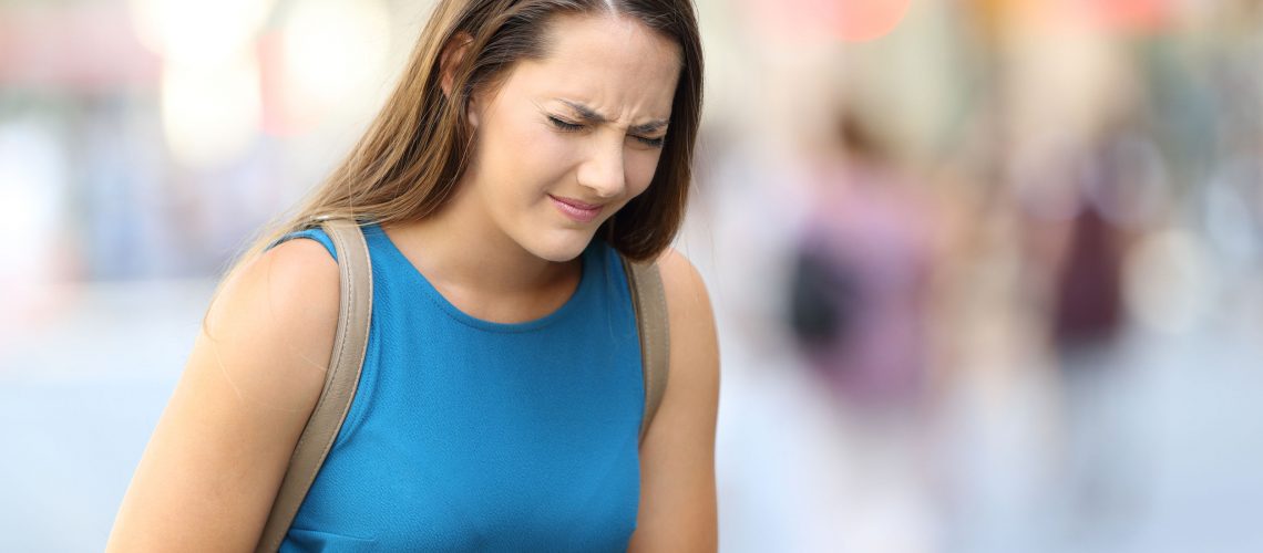 Single woman suffering belly ache outdoors in the street